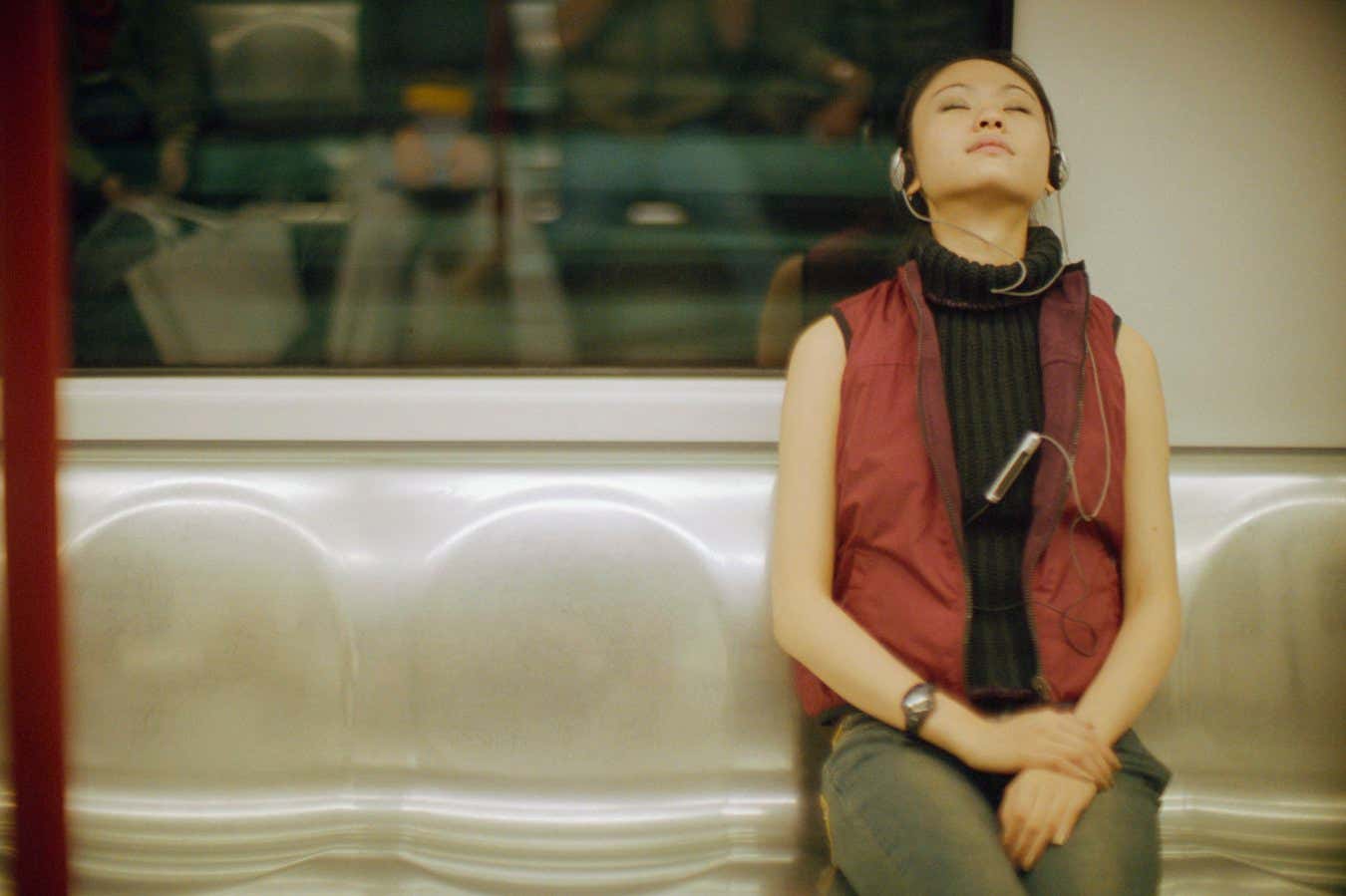 A woman on a subway with her eyes shut