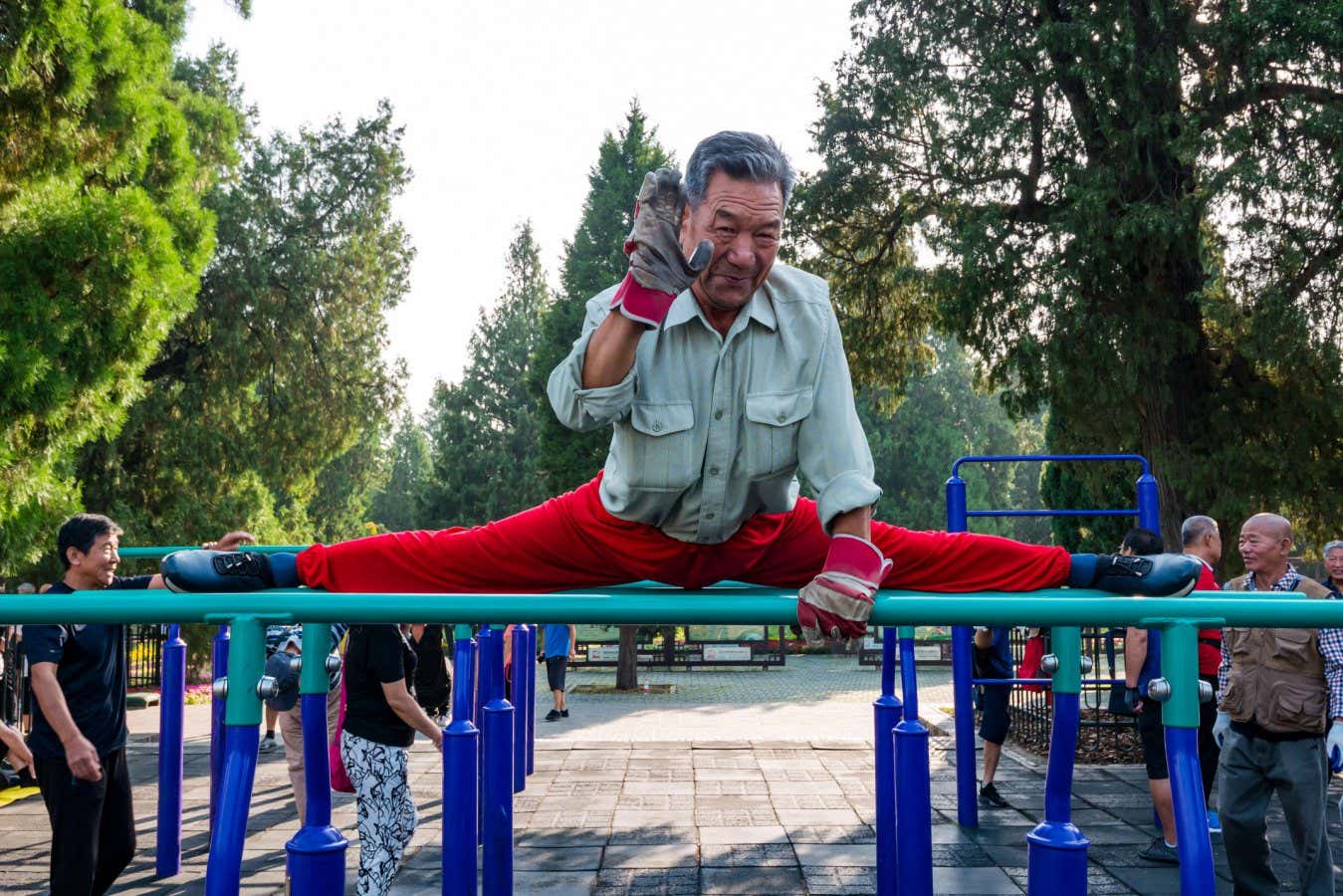 2AWNXNX Older Chinese man exercising in outdoor gym doing the splits, Tiantan Park, Beijing, China, Asia